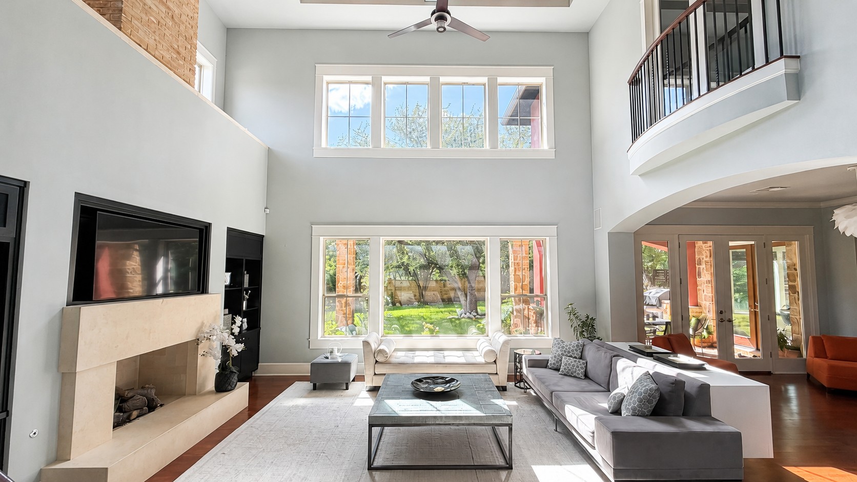 A spacious living area with soaring ceilings and an abundance of natural light from large windows.