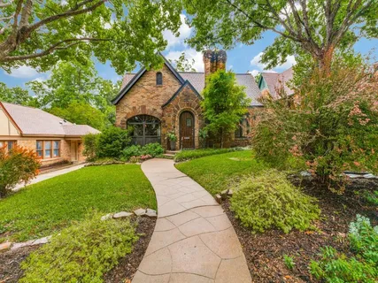 a view of a house with a small yard plants and large tree