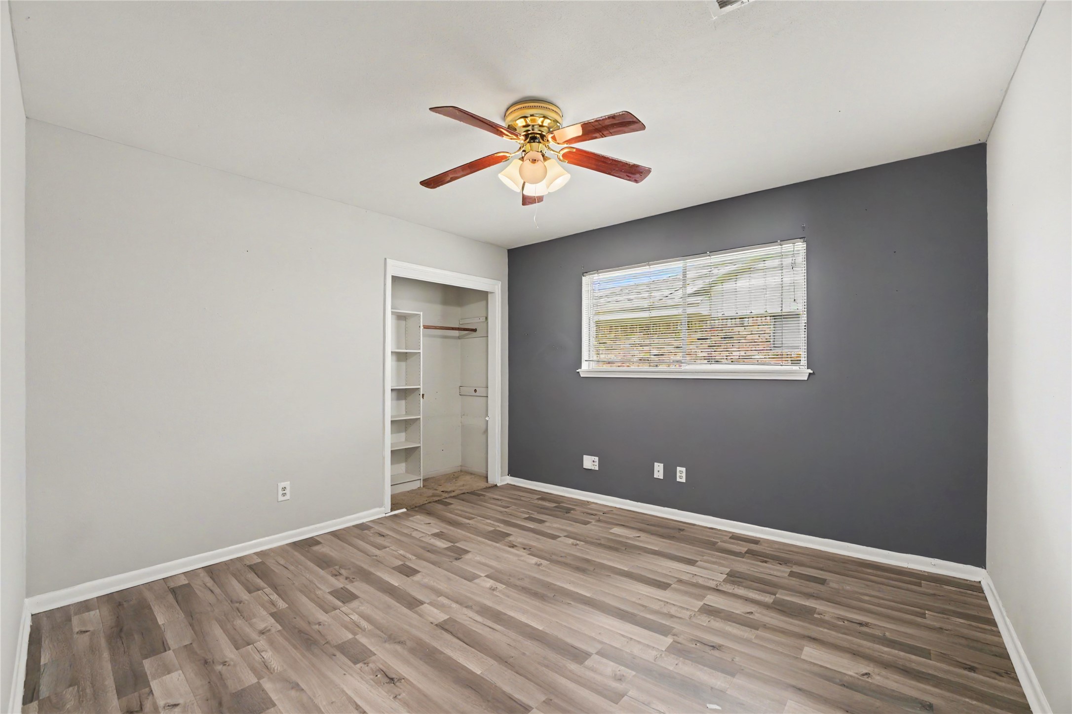 8330 Springtime Lane Houston, TX 77075 - Photo 14 of 27 Bedroom one featuring modern laminate flooring, a stylish accent wall, and a ceiling fan.