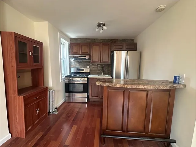 a kitchen with kitchen island wooden floors appliances and cabinets