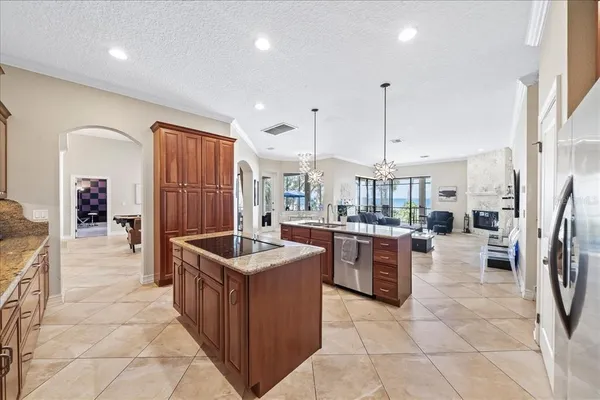 a large kitchen with a counter space a sink appliances and living room view