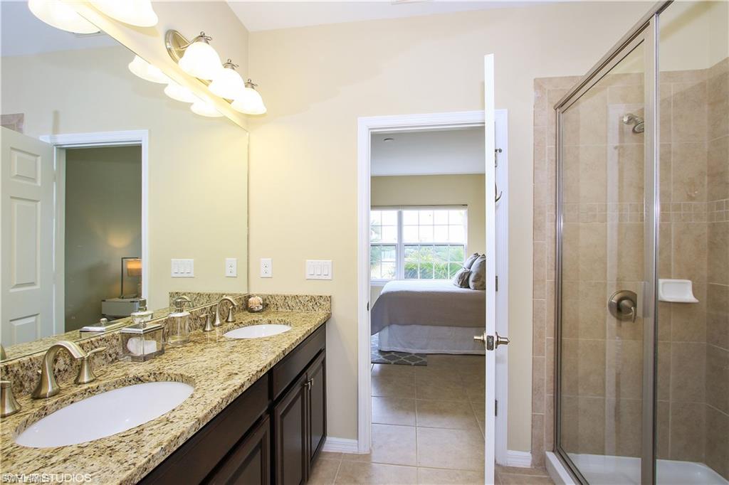 8540 Violeta Street, Unit 202 Estero, FL 34135 - Photo 15 of 22 a bathroom with a granite countertop sink a mirror and a shower
