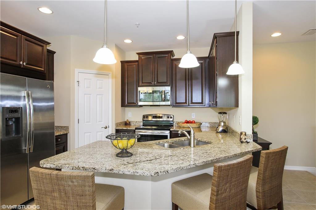 8540 Violeta Street, Unit 202 Estero, FL 34135 - Photo 2 of 22 a kitchen with stainless steel appliances granite countertop a sink a microwave and wooden cabinets