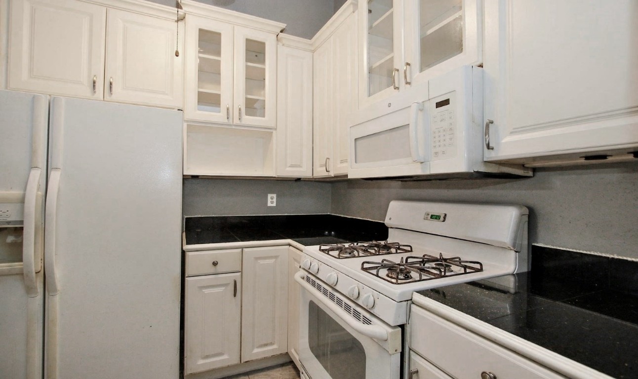 3111 Oak Rock Spring, TX 77373 - Photo 10 of 21 a kitchen with granite countertop white cabinets and white appliances
