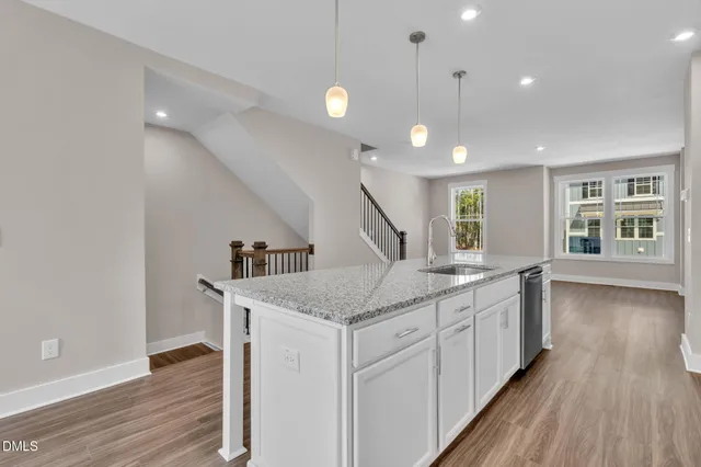 a kitchen with stainless steel appliances granite countertop a sink a stove and a wooden floors
