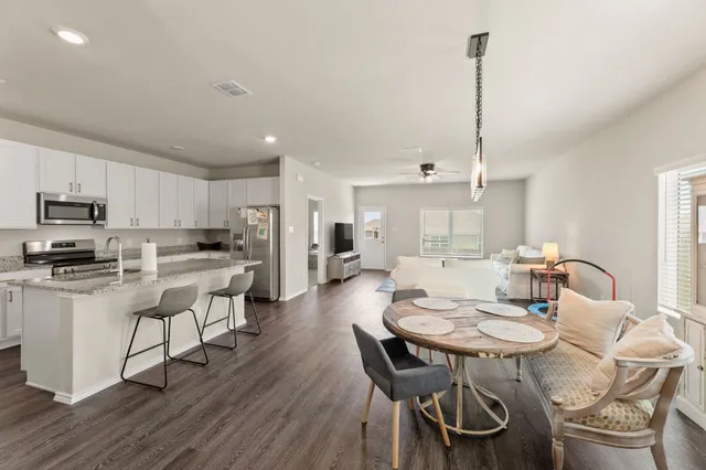 a kitchen with stainless steel appliances kitchen island granite countertop a dining table chairs and sink