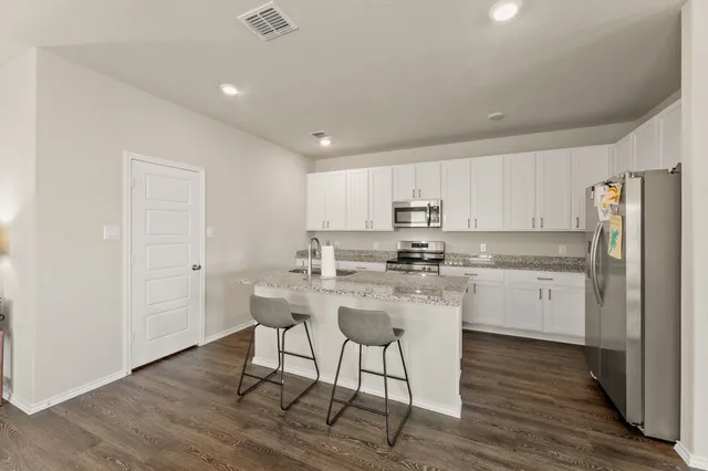 a kitchen with a sink a refrigerator and white cabinets