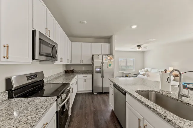 a kitchen with stainless steel appliances granite countertop a sink stove microwave and refrigerator