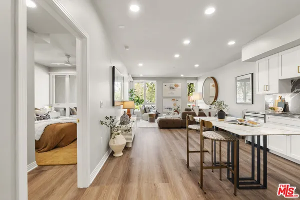 a living room with furniture kitchen view and a wooden floor