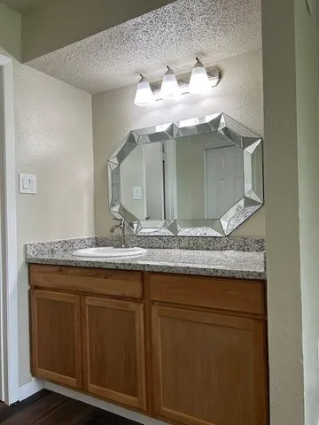 a bathroom with a granite countertop sink and a mirror