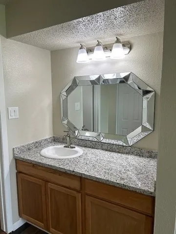 a bathroom with a granite countertop sink and a mirror