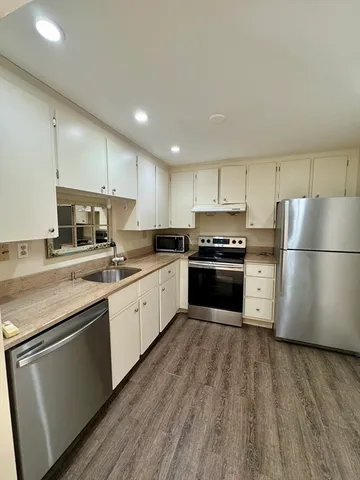 a kitchen with granite countertop a refrigerator and a stove top oven