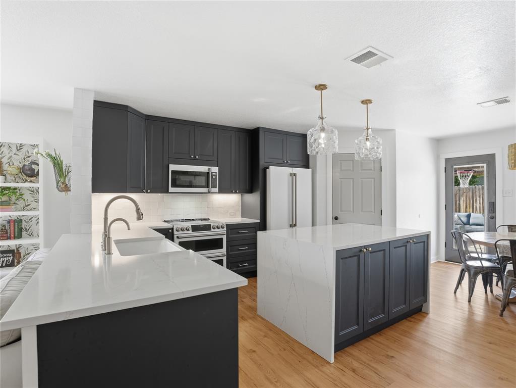 12724 Carpenter Lane Rhome, TX 76078 - Photo 3 of 37 Modern kitchen featuring dark cabinetry, stainless steel appliances, and white countertops