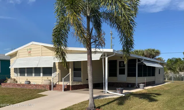 a view of a house with a yard and palm trees