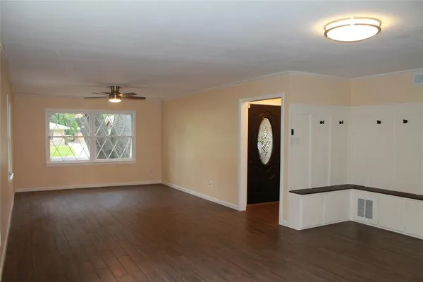 an empty room with wooden floor mirror and window