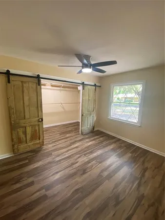 an empty room with wooden floor fan and windows