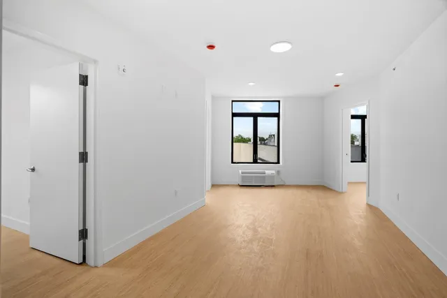 a view of an empty room with window and wooden floor