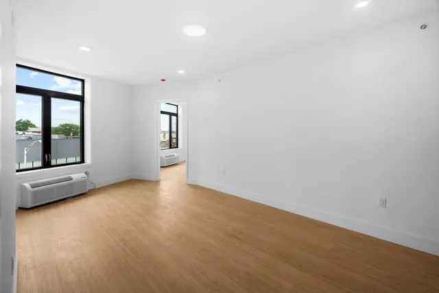 a view of an empty room with a window and wooden floor