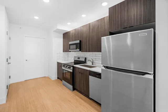 a kitchen with stainless steel appliances granite countertop a refrigerator stove a sink and a microwave with wooden floor