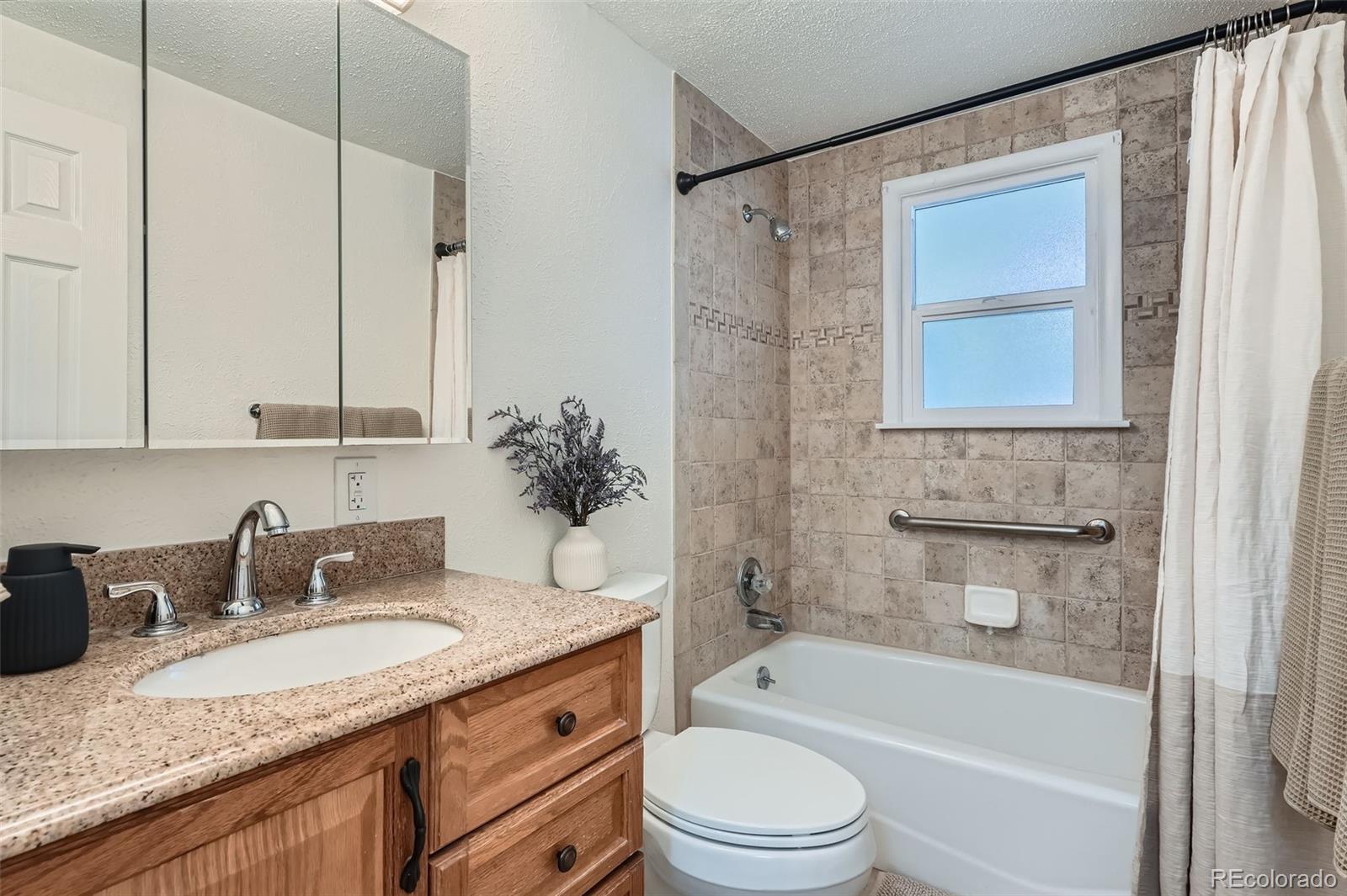 1720 South Java Way Denver, CO 80219 - Photo 11 of 28 a bathroom with a granite countertop sink toilet and shower