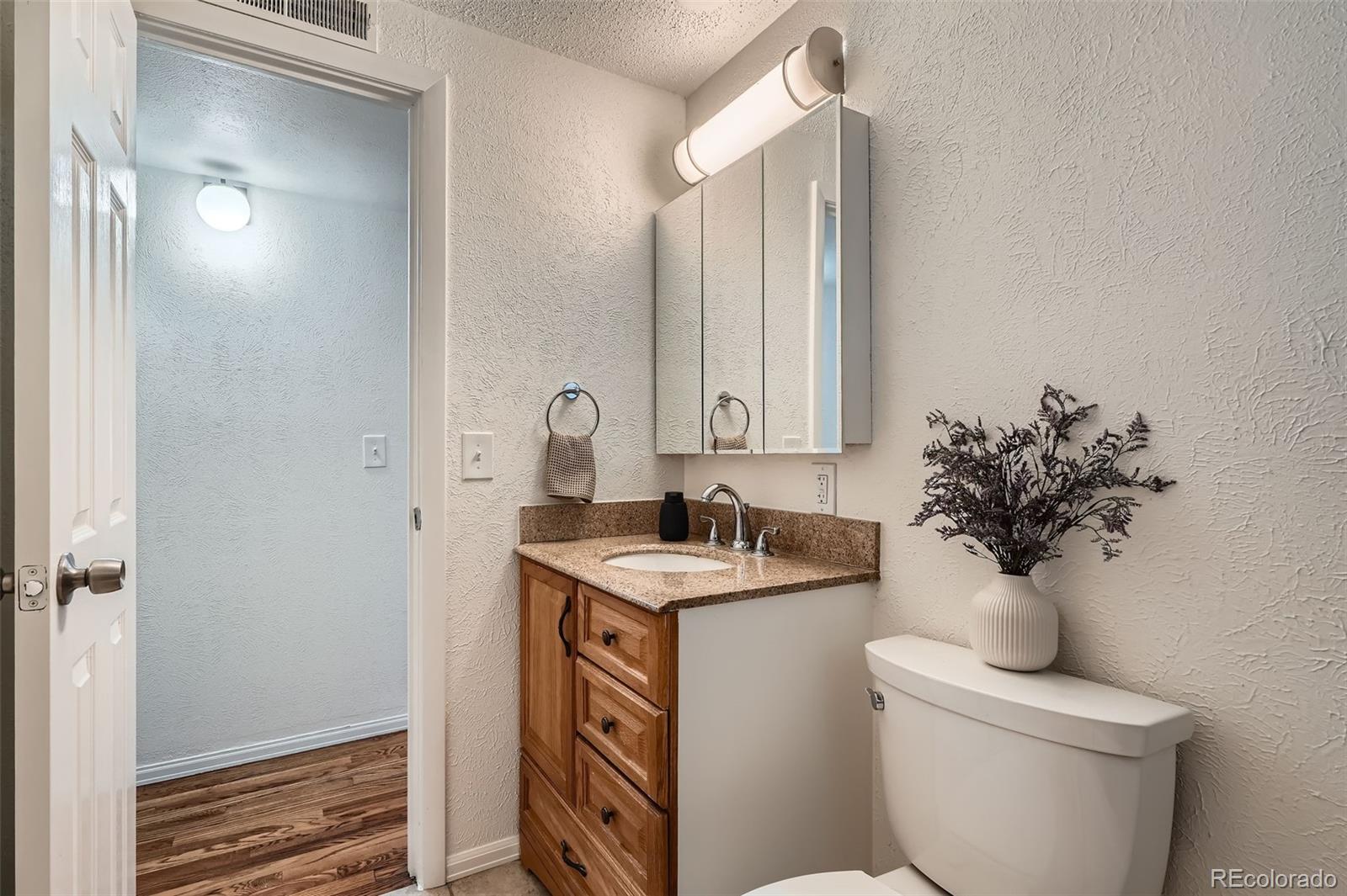 1720 South Java Way Denver, CO 80219 - Photo 12 of 28 a bathroom with a sink toilet and a mirror