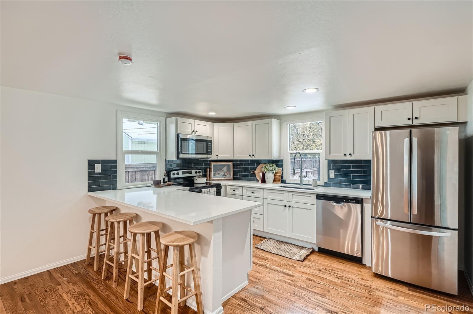 1720 South Java Way Denver, CO 80219 - Photo 6 of 28 a kitchen with a refrigerator a stove a sink dishwasher with a dining table and chairs