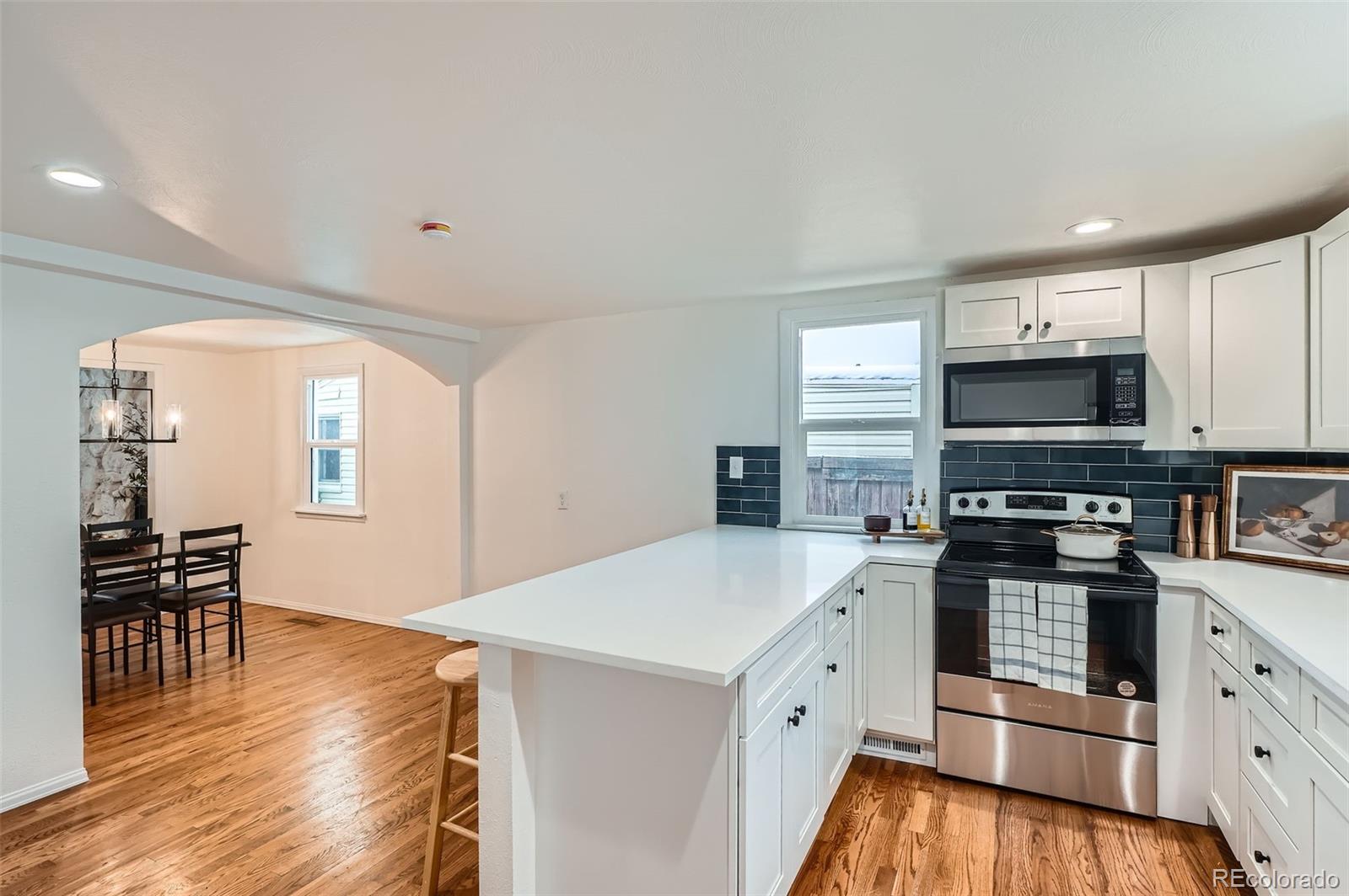 1720 South Java Way Denver, CO 80219 - Photo 8 of 28 a kitchen with granite countertop a stove a sink and a microwave