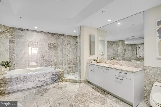 a bathroom with a granite countertop sink a toilet a large mirror and shower