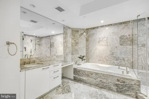 a bathroom with a granite countertop sink a mirror and a bathtub