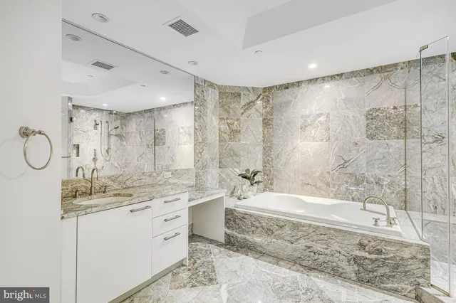 a bathroom with a granite countertop sink a mirror and a bathtub