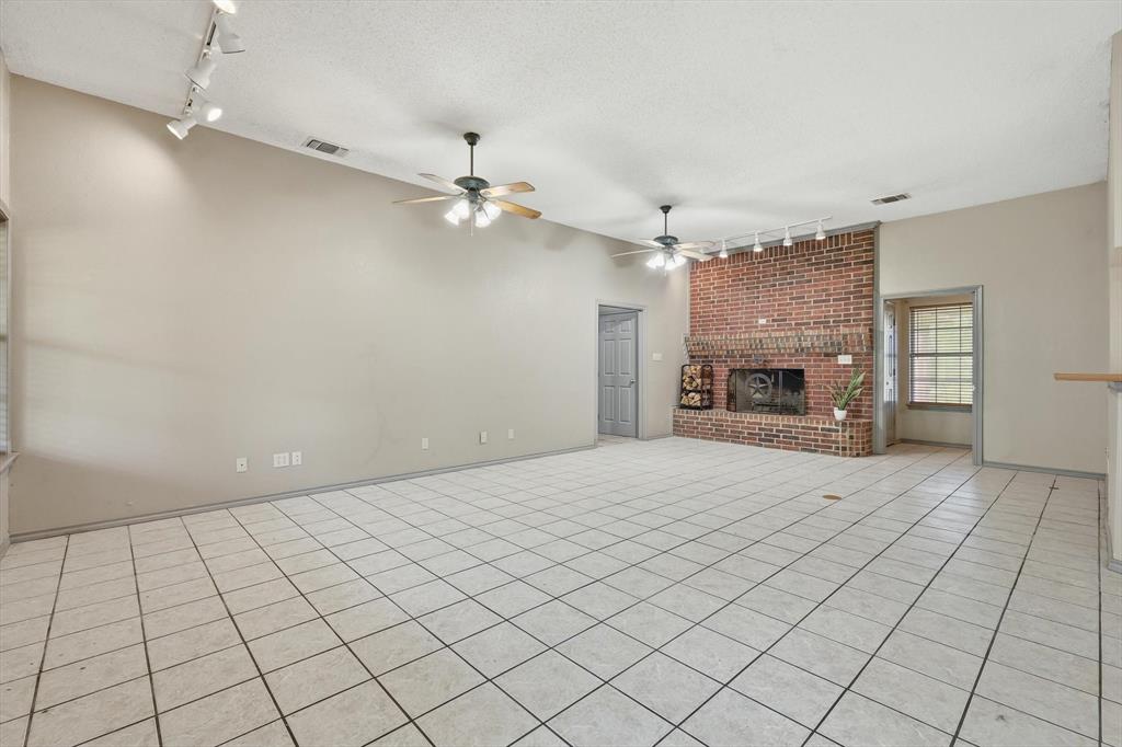 135 Private Road 2202 Decatur, TX 76234 - Photo 6 of 40 Unfurnished living room featuring track lighting, a textured ceiling, a fireplace, light tile patterned floors, and a ceiling fan