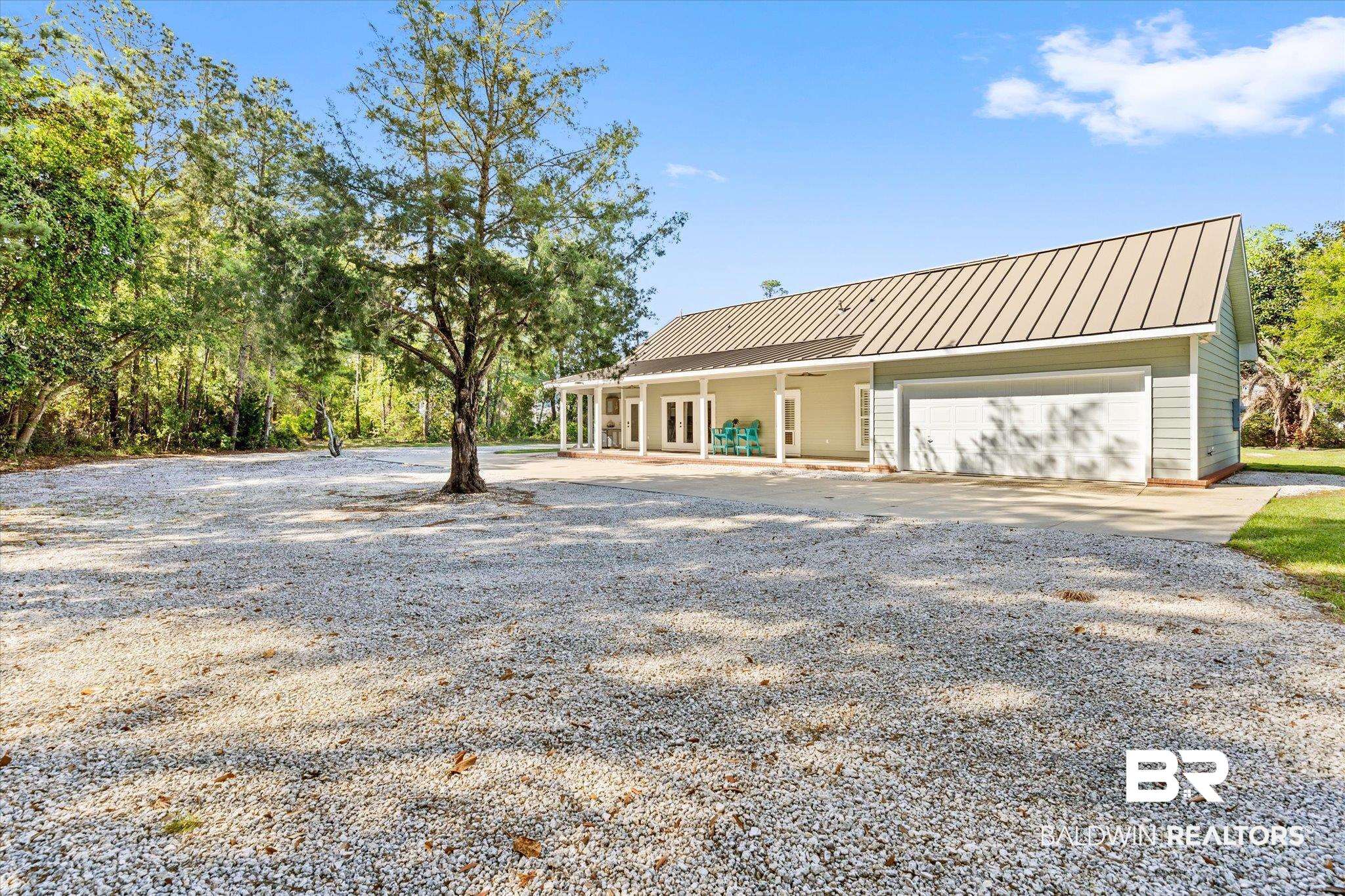 4947 Look Rook Road Orange Beach, AL 36561 - Photo 20 of 24 Back of house featuring a standing seam roof, gravel driveway, metal roof, and a garage