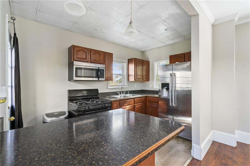 339 Brown Street Rochester, PA 15074 - Photo 7 of 17 a kitchen with stainless steel appliances granite countertop a refrigerator a stove and a sink with wooden floor