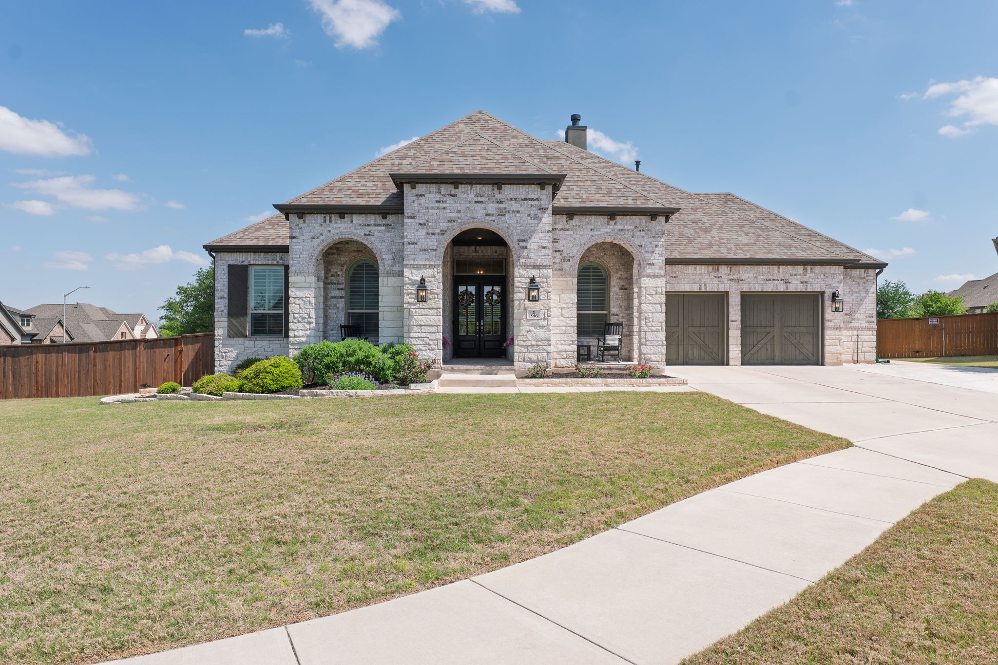 1916 Boulderback Cove Leander, TX 78641 - Photo 1 of 1 The property features a stone exterior with arched entryways, a paved driveway, and a well-maintained front yard with landscaping