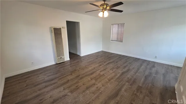 a view of a big room with wooden floor and windows