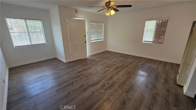 a view of an empty room with a window and wooden floor