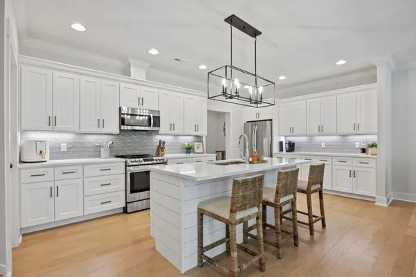 a kitchen with stainless steel appliances kitchen island granite countertop a sink a stove and a wooden floors