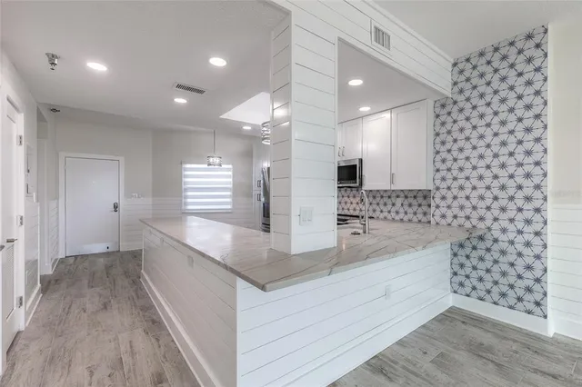 a large white kitchen with a granite countertop sink and a large mirror