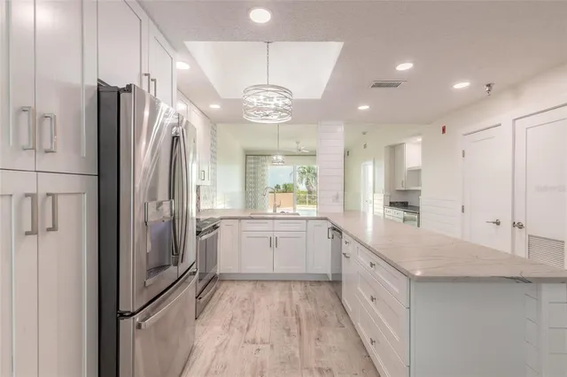 a large kitchen with a large window a sink stainless steel appliances and cabinets