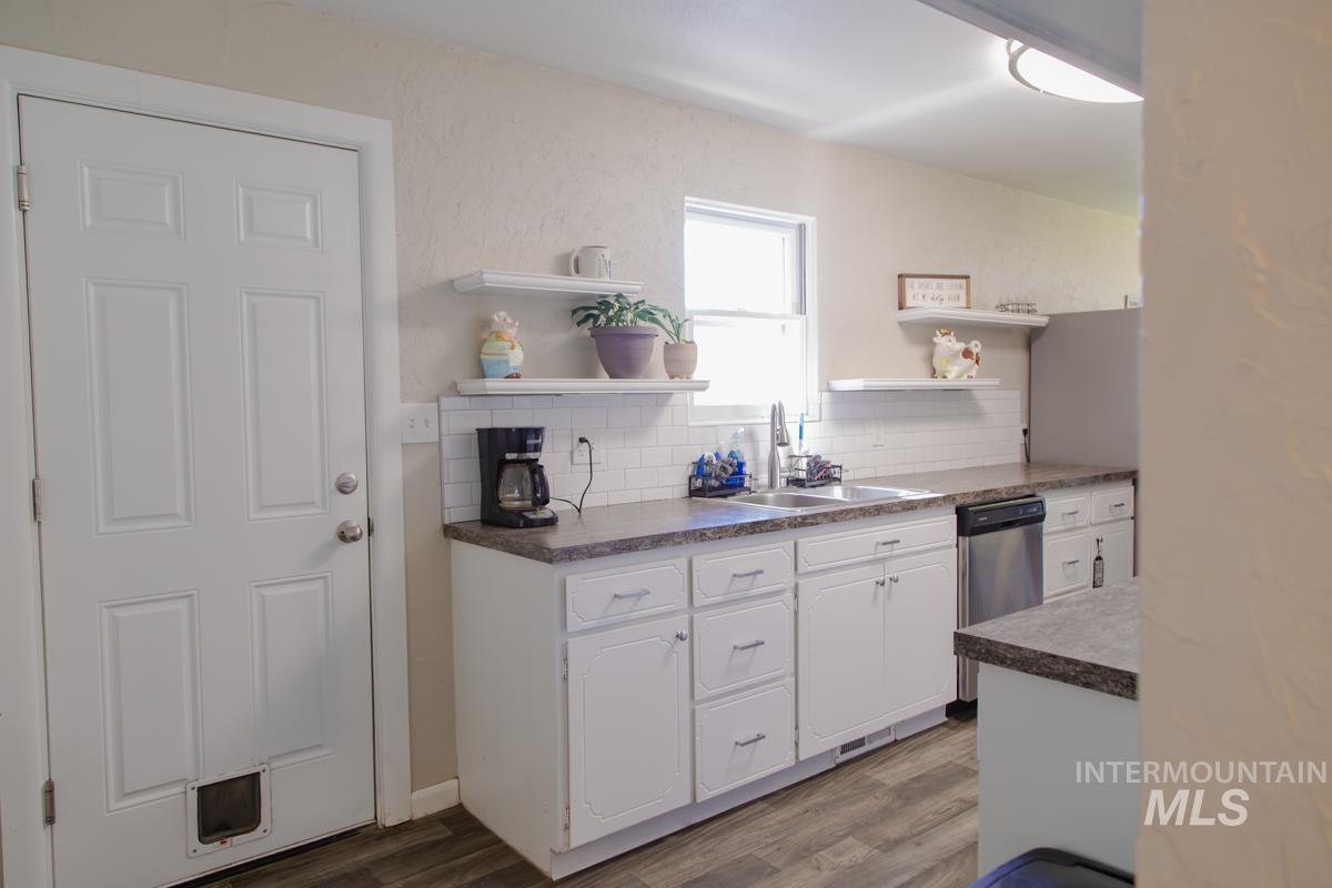 1404 Rochester Street Caldwell, ID 83605 - Photo 18 of 29 Kitchen featuring white cabinetry, a double basin stainless steel sink, wood-finish flooring, and a subway tile backsplash