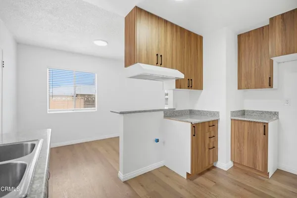 a kitchen with stainless steel appliances granite countertop a stove a sink and a refrigerator with wooden floors