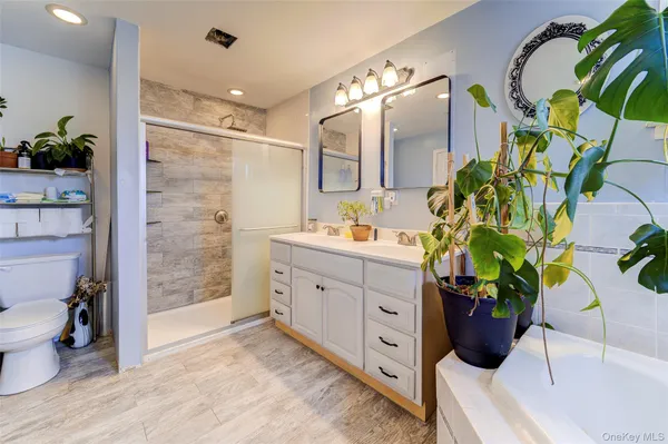 a bathroom with a double vanity sink and a potted plant