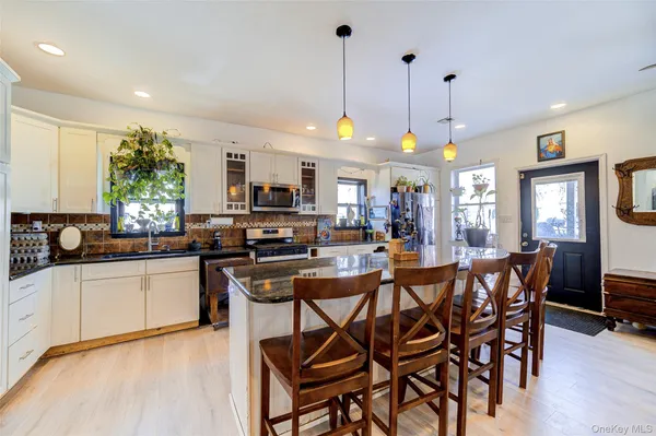 a kitchen with stainless steel appliances kitchen island granite countertop a table chairs and a refrigerator