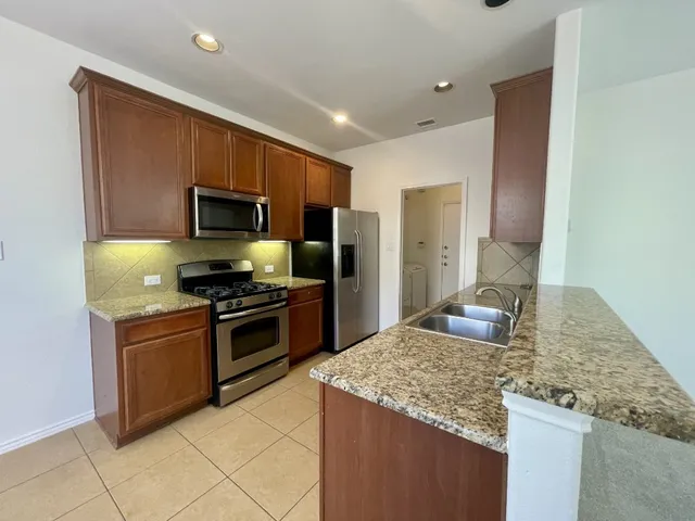 a kitchen with kitchen island granite countertop a sink and stainless steel appliances