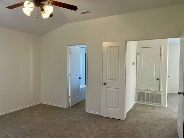 an empty room with a chandelier fan and closet area