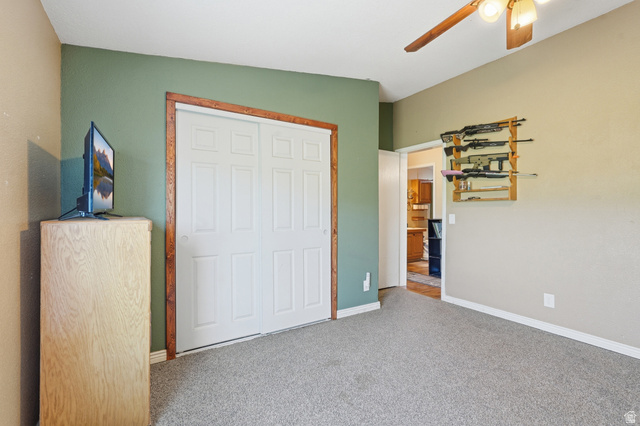 8066 North Valley View Heights Preston, ID 83263 - Photo 21 of 34 Room with carpet flooring, a ceiling fan, and bi-fold closet doors with wood trim