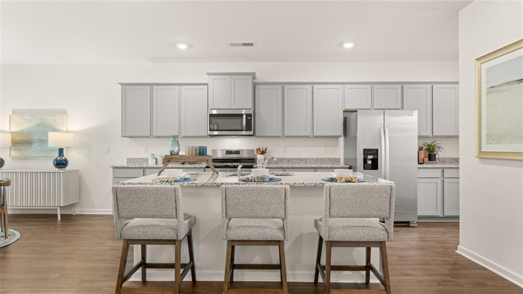 56 Weymouth Drive Locust Grove, GA 30248 - Photo 12 of 62 a kitchen with stainless steel appliances a stove a sink a refrigerator white cabinets and wooden floor