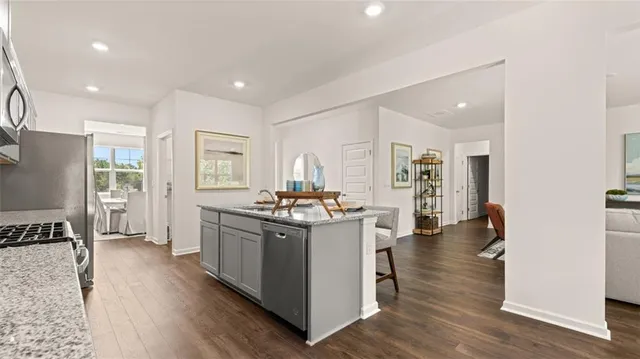a living room with furniture a wooden floor and kitchen view