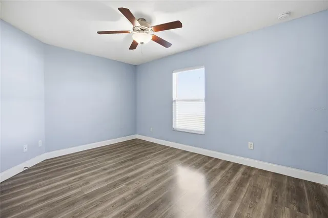an empty room with a window and ceiling fan