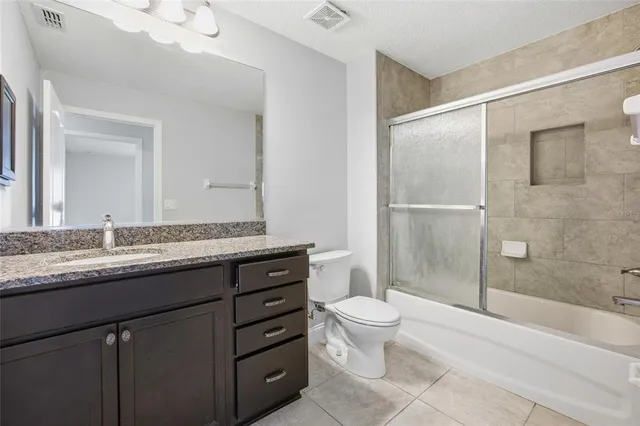 a bathroom with a granite countertop sink toilet mirror and shower
